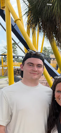 a man and woman posing for a photo in front of a roller coaster